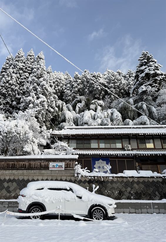 雪に覆われた古民家と車