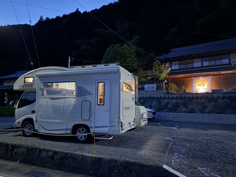 夕暮れの古民家とキャンピングカー